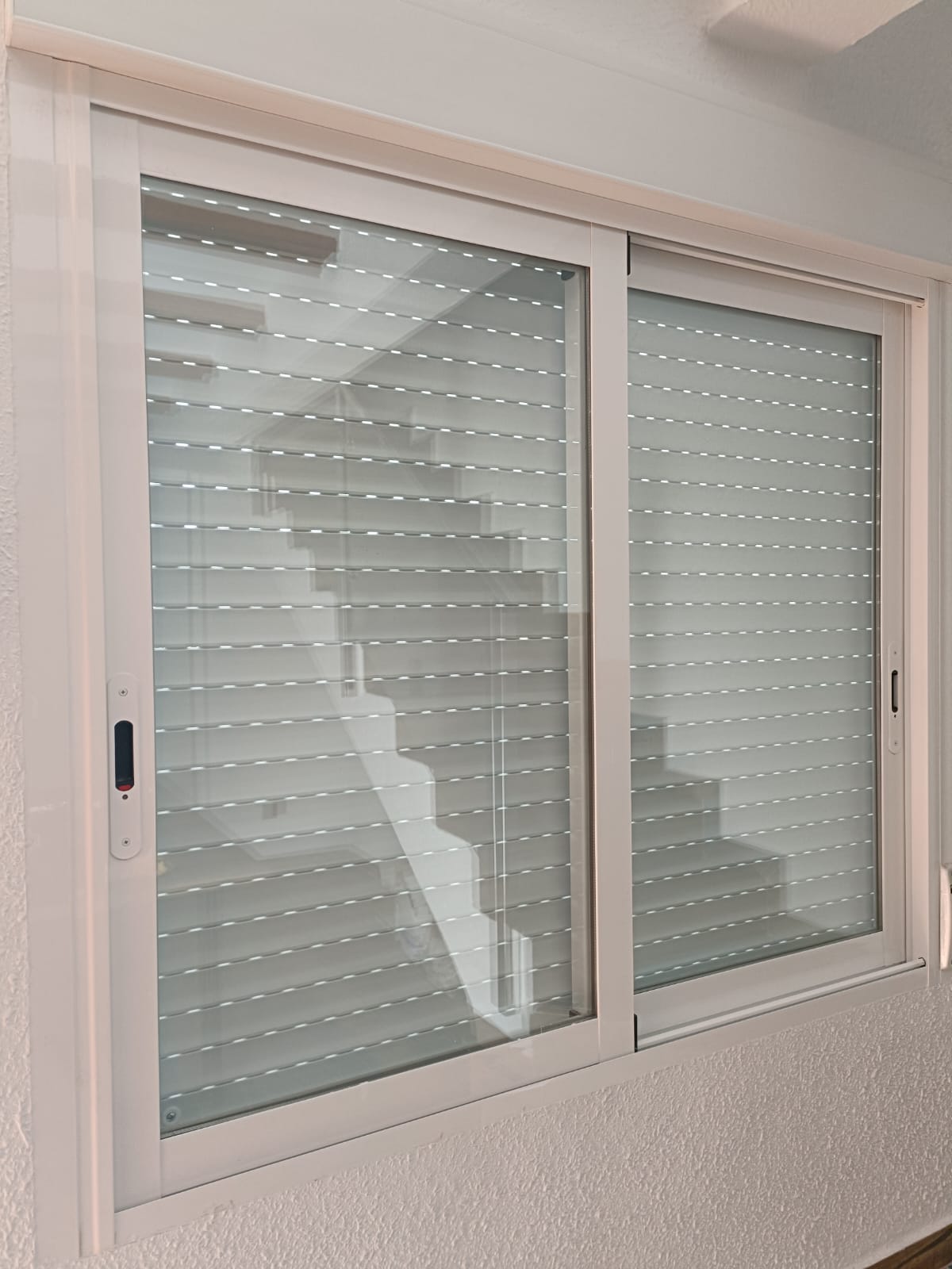 Ventana corredera blanca con persiana