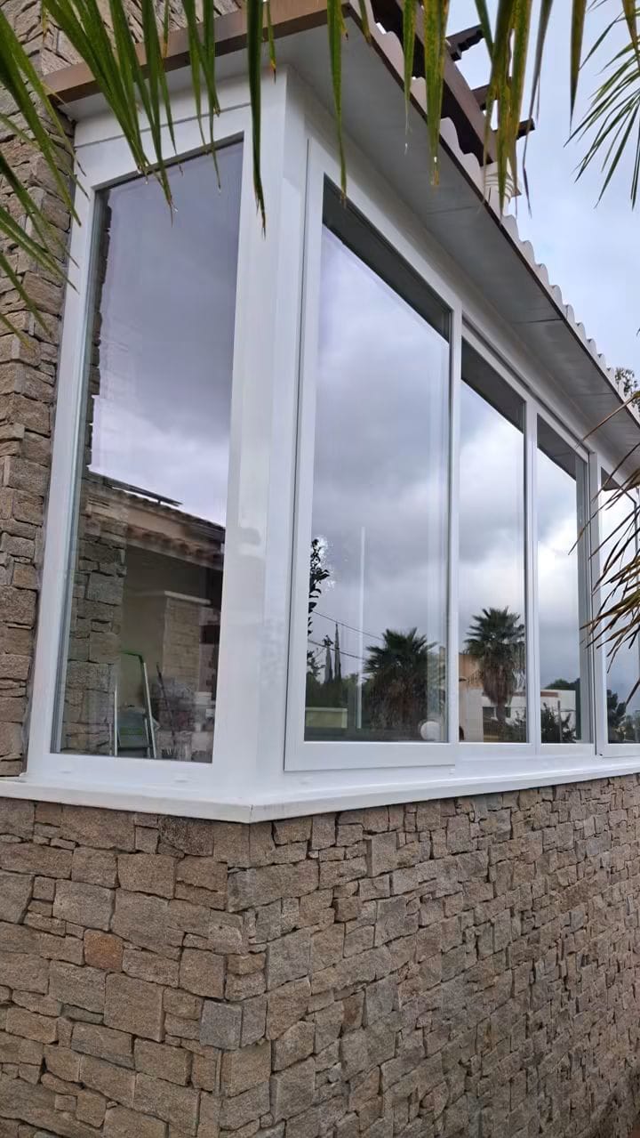 Cerramiento exterior blanco sobre fachada de piedra